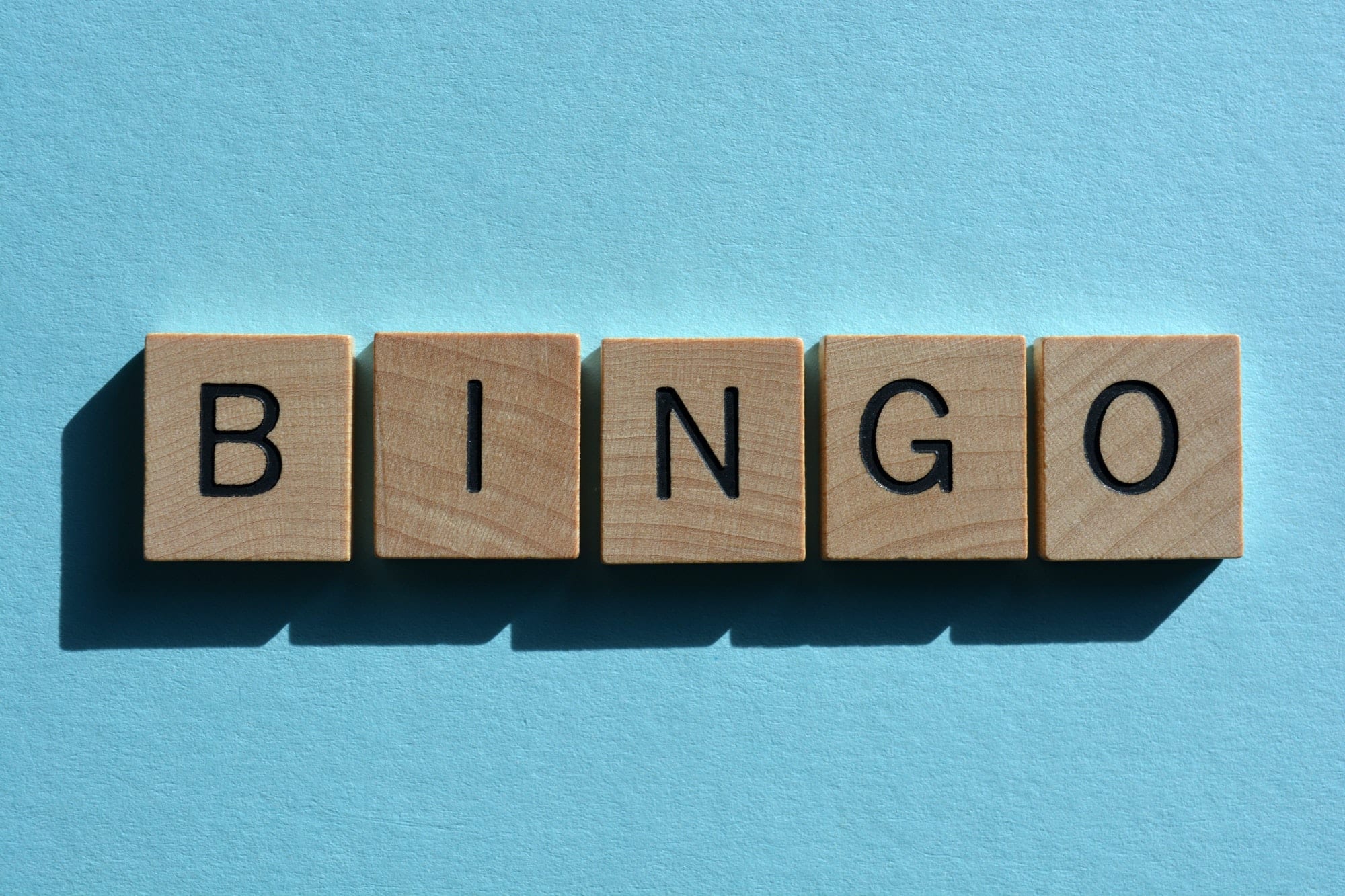 Bingo. Word in 3D wooden alphabet letters on a bright blue background with copy space