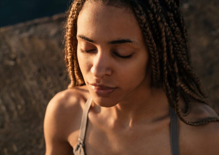 African woman practicing yoga meditation at the beach