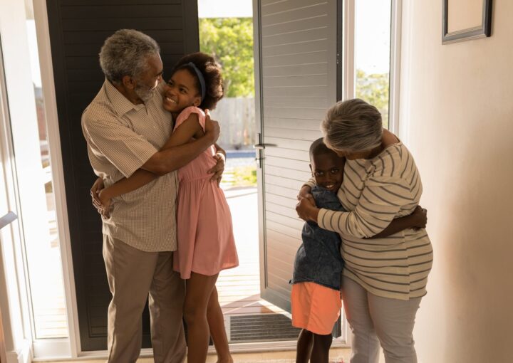 Front view of happy African American grandparents hugging their grandchildren at home