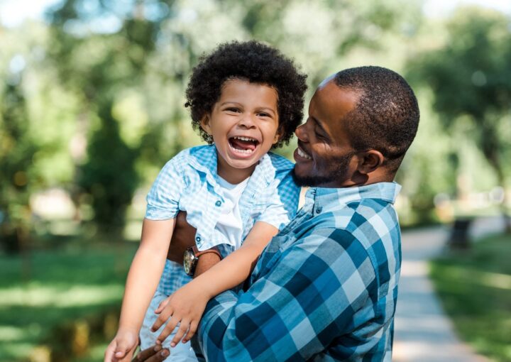 happy african american man holding in arms cheerful son