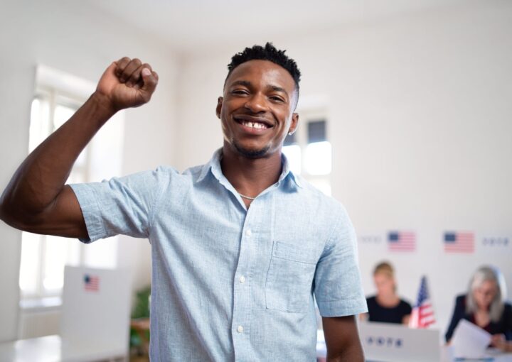 Happy african-american man voter looking at camera in the polling place, usa elections