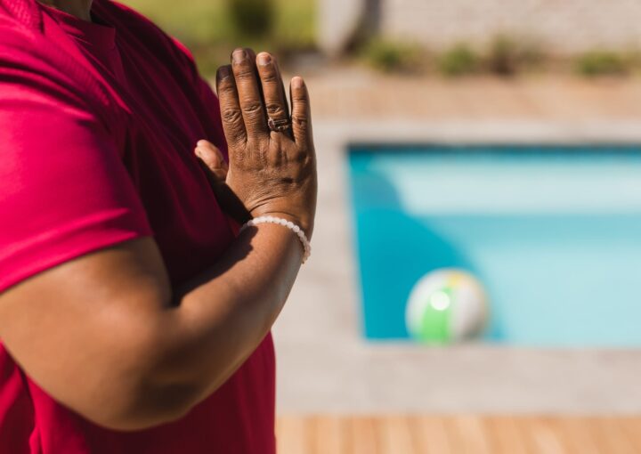 senior woman performing yoga next to a swimming pool in the backyard of home