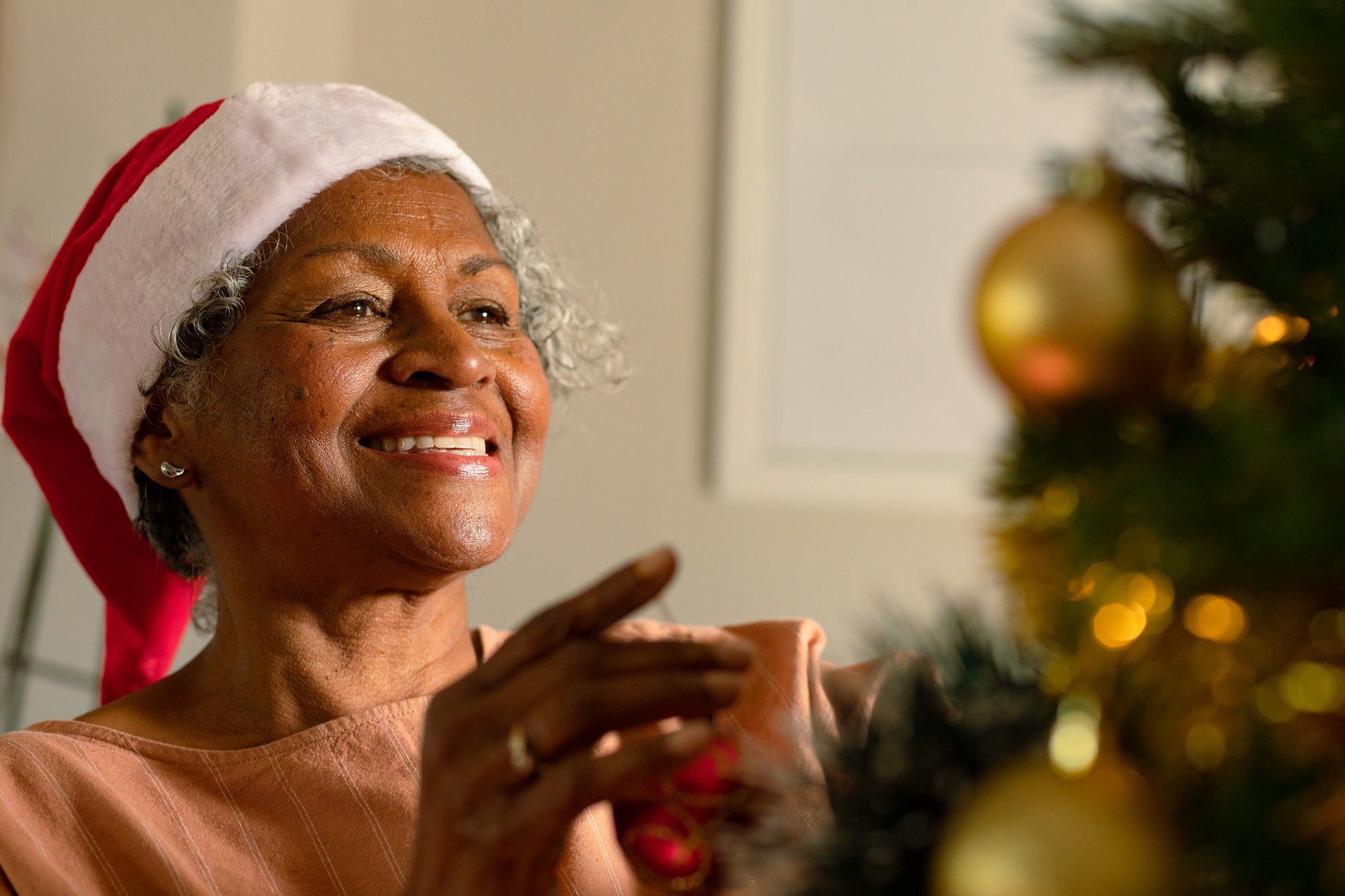 Happy african american senior woman decorating christmas tree