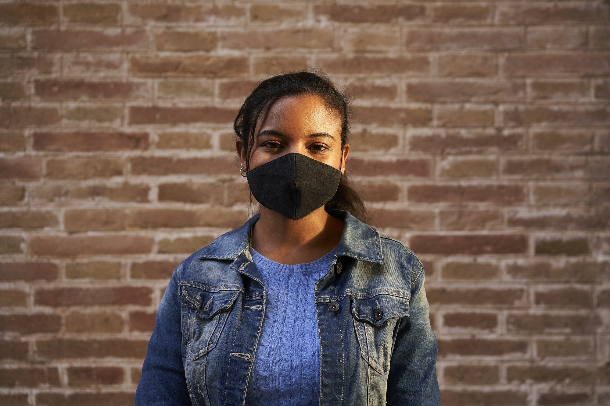Portrait of an African American black woman wearing face mask looking at camera outdoors